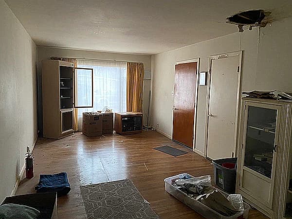 Before picture 2 - Living room view showing water damage and outdated fixtures
