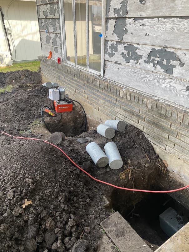 Holes dug to start installing pressed piers to correct 2 inch slope